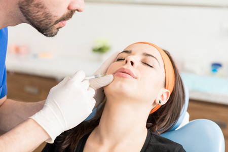 Cropped male doctor injecting fillers that adds instant volume and contour to the lips on a temporary basisの写真素材