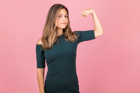 Portrait of young woman flexing muscles to show her strength in studioの写真素材