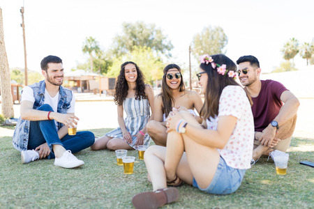 Cheerful trendy friends talking while having fun at music festival in summerの写真素材