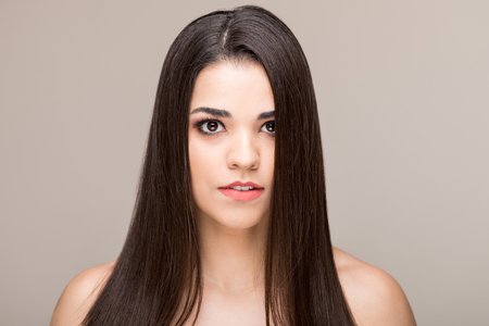 Closeup of attractive mid adult woman with long brown hair against colored backgroundの写真素材