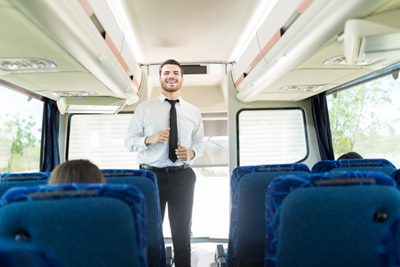 Handsome male driver in uniform standing inside tourist busの写真素材