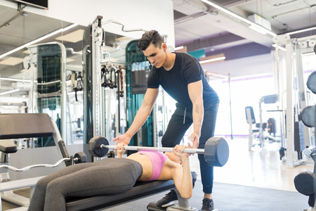 Male workout partner motivating his woman doing workout in health clubの写真素材