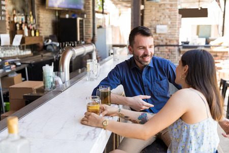 Male and female friends talking while having beer at restaurant