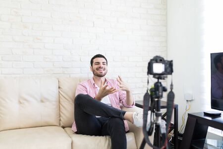 Young Hispanic male blogger recording video blog at homeの写真素材