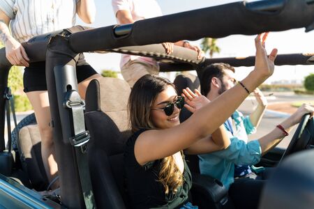 Latin woman enjoying music during road trip with friends in summer
