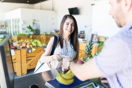 Gorgeous Caucasian woman using a credit card to pay for her groceries at storeの写真素材
