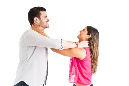 Man and woman strangling each other while standing against isolated background