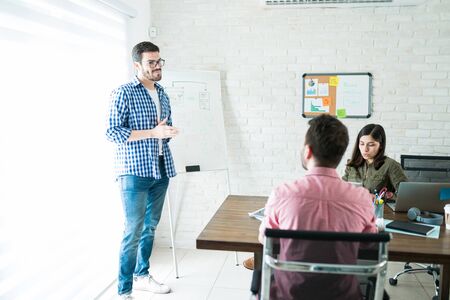 Young professional presenting business project to team at office meeting