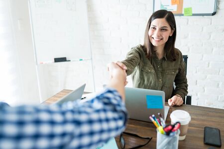 Smiling businesswoman shaking hands with coworker during office meetingの写真素材
