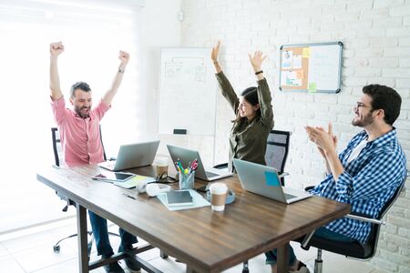 Professionals cheering for successful deal after meeting at conference room in officeの写真素材