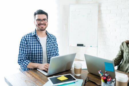 Handsome Latin entrepreneur using laptop while working at officeの写真素材
