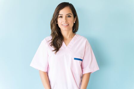 Beautiful mid adult Caucasian nurse wearing scrubs over blue backgroundの写真素材