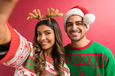 Portrait of beautiful woman enjoying Christmas holiday with handsome man against red background