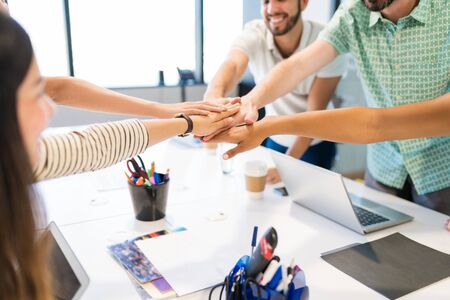 Cropped image of business team stacking hands over desk during meeting at officeの写真素材