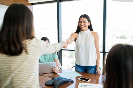 Young businesswomen shaking hands over table in meeting room at officeの写真素材