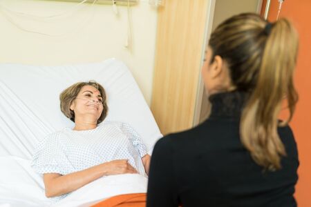 Smiling senior woman looking at daughter during visit in hospitalの写真素材