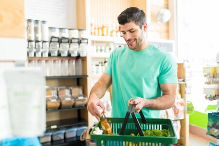 Smiling Hispanic man buying food product in grocery storeの写真素材