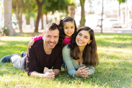 Smiling Family Lying On Grass At Park During Sunny Day