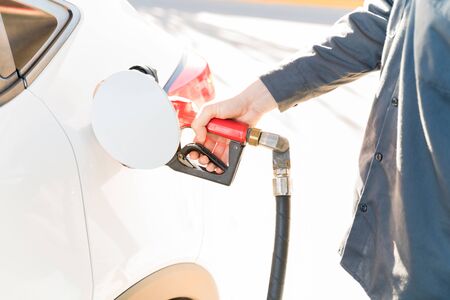 Midsection of male staff refueling car at gas station