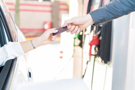Cropped hand of customer making payment through credit card at gas stationの写真素材
