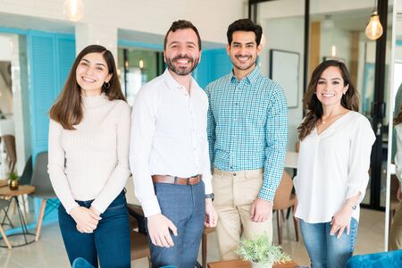Smiling male and female coworkers standing together at coworking spaceの写真素材