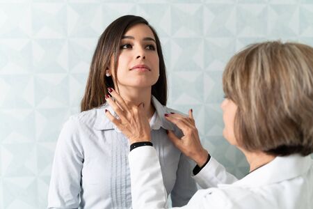 Caucasian woman visiting female family doctor for thyroid checkupの写真素材