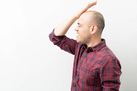 Profile view of a Caucasian man hitting his forehead and feeling frustrated in a studio
