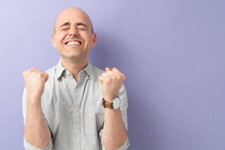 Caucasian man with eyes closed and clenched jaw being hopeful and wishing for something great to happenの写真素材