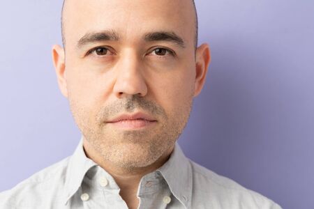 Close portrait of a good looking man dressed casual in a studio and looking serious