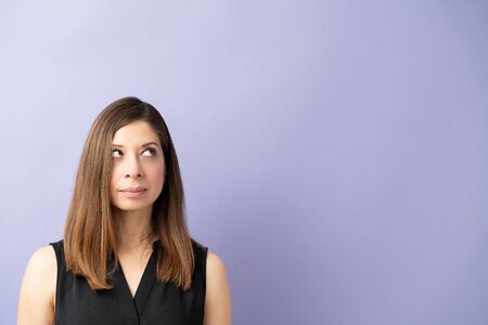 Caucasian woman in her 40s dresses casual and looking up towards copy space in a studio