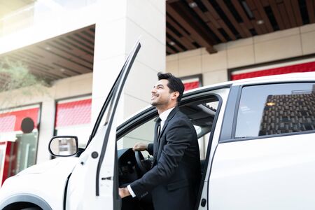 Smiling young male business executive getting out from carの写真素材