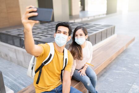 Man taking selfie with woman while sitting on seat during coronavirus outbreak in city