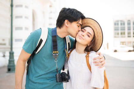 Hispanic young man kissing beautiful girlfriend during weekend trip in city