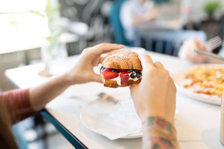 Cropped hands of woman having sweet food in restaurant