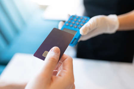 Cropped hand of man making payment through credit card at cafe