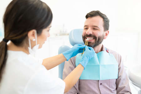 Caucasian female odontologist checking teeth of patient at dental clinic