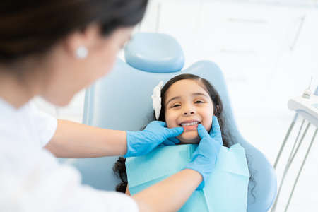 Female dentist checking teeth of little patient at dental clinicの写真素材