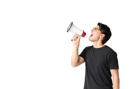 Hispanic young man making announcement using megaphone in studioの写真素材