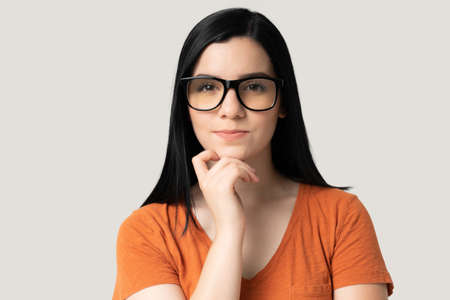 Closeup of confident pretty young woman in eyeglasses against gray background