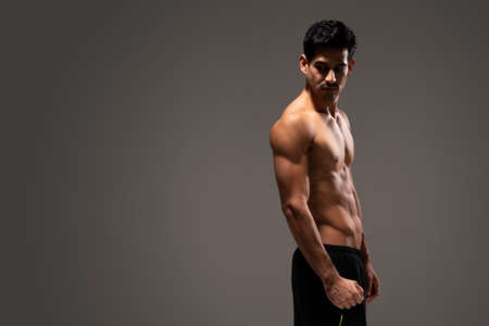 Side view of Latin young muscular man in shorts looking down