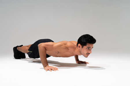 Full length of shirtless muscular young man doing push ups in studioの写真素材