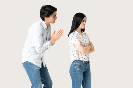 Hispanic man apologizing disappointed young woman with hands claspedの写真素材