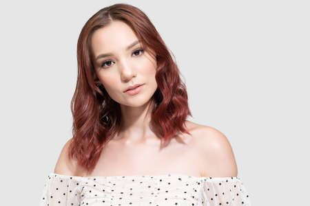 Confident female fashion model wearing off shoulder top against gray background