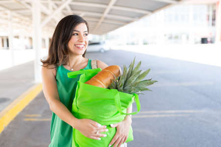 Smiling Caucasian woman looking away while carrying grocery bagの写真素材