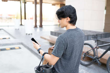 Young delivery man using map on smartphone while walking on footpathの写真素材