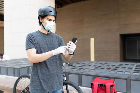 Young delivery man using map on smartphone during coronavirus outbreak