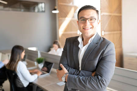 Portrait of confident caucasian businessman standing with his arms crossed in office