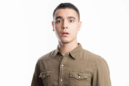 Surprised and shocked Latin man standing in a studio against a white background with casual clothing
