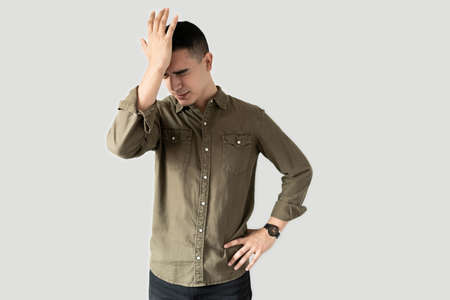 Young man bumping his head after remembering something he forgot in a studio
