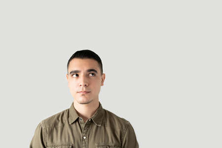 Latin young man looking towards copy space and trying to organize his thoughts and ideas and looking...